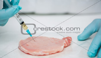 Close up of gloved researcher's hands injecting meat