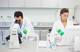 Researchers using microscope and computer in the lab