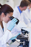 Female scientific researcher using microscope in lab