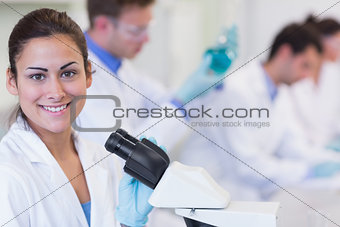 Smiling female with researchers working on experiments in lab