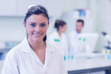 Female researcher with colleagues in background at lab