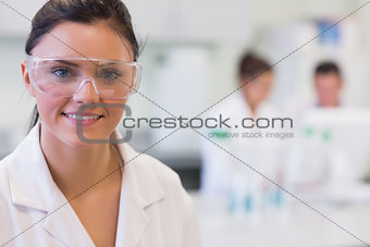 Female researcher with colleagues in background at lab