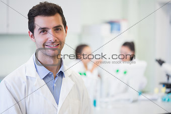 Smiling researcher with colleagues in background at lab