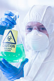 Scientist in protective suit with hazardous chemical in flask