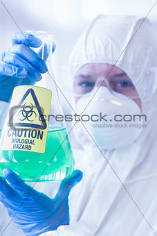 Scientist in protective suit with hazardous chemical in flask