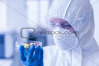 Scientist in protective suit analyzing pills