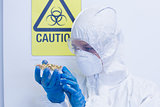 Scientist in protective suit with sprouts in laboratory