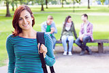 College girl smiling with blurred students in park