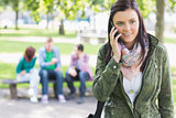 College girl using mobile phone with students in park