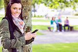 College girl text messaging with blurred students in park