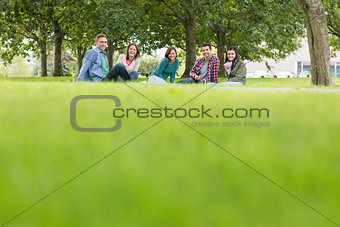 Young college students sitting on grass in park