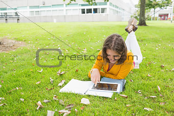 Smiling female student using tablet PC in lawn