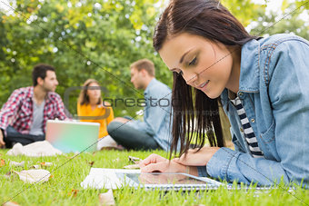 Female using tablet PC while others using laptop in park