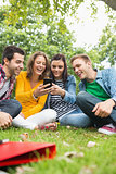 Happy college students looking at mobile phone in park
