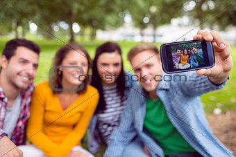Male taking picture with college friends in park