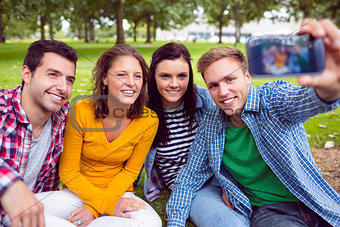 Male taking picture with college friends in park