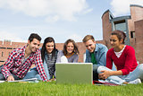 Students using laptop in lawn against college building