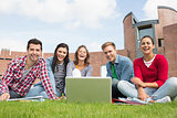Students with laptop in the lawn against college building