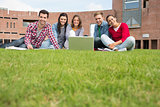 Students with laptop in the lawn against college building