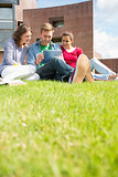 Students using tablet PC in the lawn against college building