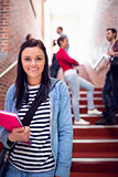 Female holding books with students on stairs in college
