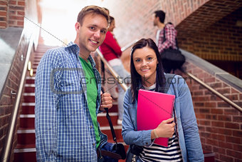 Couple with students behind on stairs in college