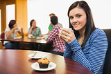 Smiling female having coffee and muffin at  coffee shop