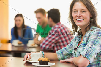 Smiling female having coffee and muffin at  coffee shop