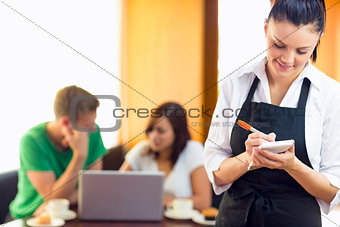 Waitress writing an order with students using laptop at  coffee shop