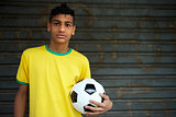Young Brazilian soccer player holds football