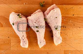 Chicken drumsticks on a wooden board with herbs