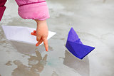 Two paper ship in puddle and child's hand