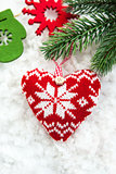 Knitted  heart on the snow with fir-tree branch 