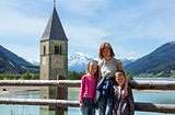 The bell tower in Reschensee and family (Italy).
