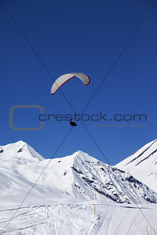 Paraglider in sunny snowy mountains