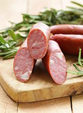Dried sausage with  fresh rosemary on a wooden background