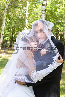 a happy newly-married couple under the veil
