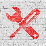 Icon of Crossed Screwdriver on White Brick Wall.