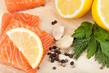 Salmon on cutting board with lemons and herbs