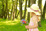 beautiful little girl on nature with a bouquet of flowers