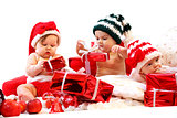 Three babies in xmas costumes playing with gifts