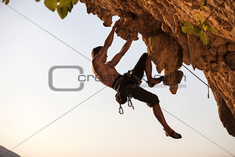Rock climber against sky at sunset