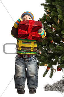 Cute little boy with gift near Christmas tree