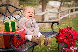 Young Toddler Child Sitting on Bench with Christmas Gifts Outsid