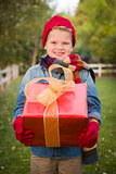 Young Boy Wearing Holiday Clothing Holding Christmas Gift Outsid