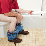 Man Using Toilet Paper in Bathroom