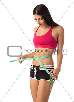 Young girl checking her waistline with a measuring tape