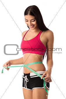 Beautiful young girl checking her waistline with measuring tape