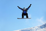 Snowboarder jumping against blue sky background