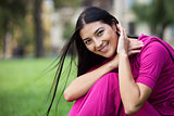 Portrait of beautiful young woman sitting on grass in park